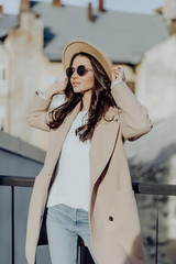 Street portrait of young pretty woman wearing hat and coat walking down at the street