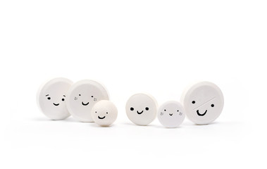 White different tablets on white background. white pills with funny faces, emotional character. family medicine creative concept. close up, copy spase