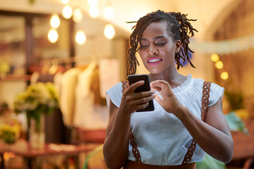 Beautiful young Black woman checking social media on her smartphone