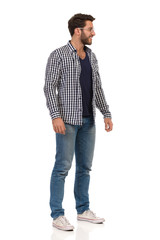 Smiling Man In Sneakers, Jeans, Lumberjack Shirt And Glasses Is Standing And Looking Away