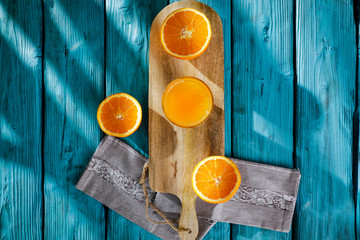 Fresh orange fruits for juice on blue wooden board with shadow. Free space for your decoration and summer time. Healthy nutrition. 