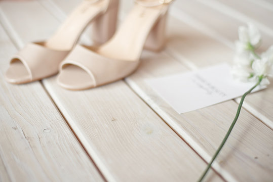 Wedding bouquet of white flowers, shoes and wedding rings on a wooden background