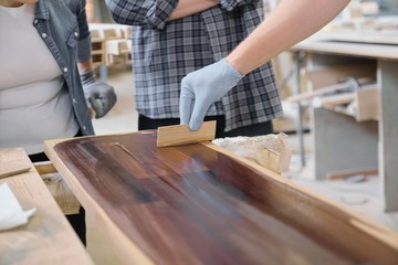 Closeup of workers hand covering wooden plank with finishing protective cover for wood