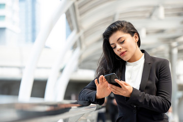 Young Latin businesswoman using smartphone outdoors