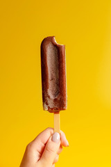 chocolate ice cream in hand on yellow background