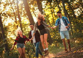 Group of four friends having fun hiking through forest together.