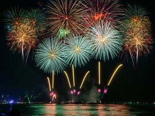 Amazing beautiful colorful fireworks display on celebration night, showing on the sea beach with multi color of reflection on water