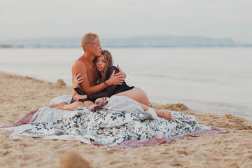 Fototapeta premium a couple in love a man and a girl meet the dawn in bed on the beach
