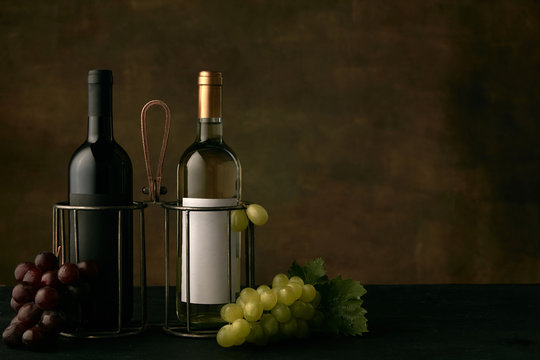 Front view of tasty fruit plate of grapes with the wine bottles on dark studio background, copy space to insert your text or image. Gourmet food and drink.