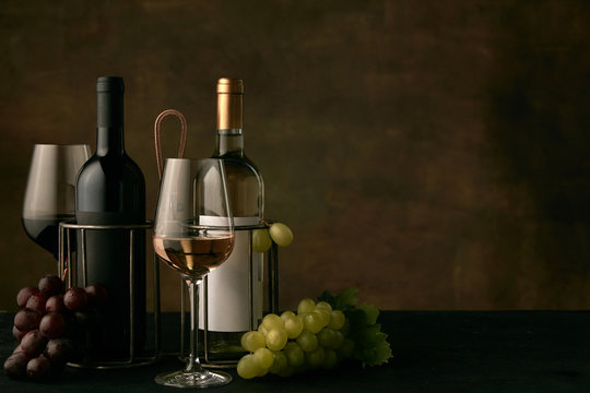 Front view of tasty fruit plate of grapes with the wine bottles and glasses on dark studio background, copy space to insert your text or image. Gourmet food and drink.