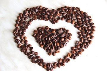 coffee beans in the shape of a heart in the heart, after roasting on the table, close-up