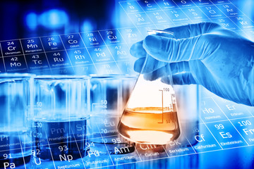 Flask in scientist hand with lab glassware background in laboratory. Science or chemical research...