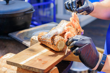 chef serves wooden desk with seafood and sweet grilled corn at the festival. Street food prepared on grill