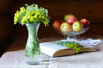 Bouquet of wild flowers in a glass vase on the table by the window.