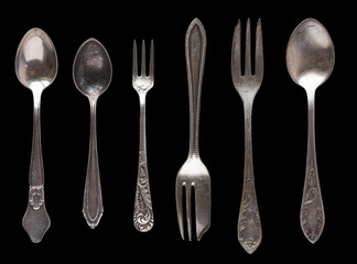 Beautiful old vintage knifes and spoons isolated on black background. Top view. Retro silverware