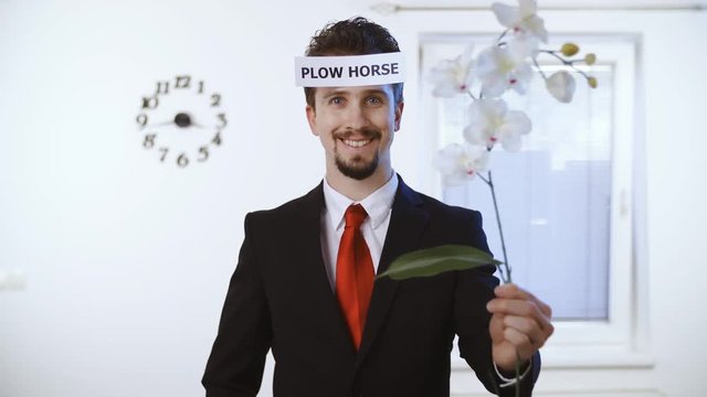 Rich businessmen plow horse for women 4K. Medium shot of a male person in focus dressed up nicely with a red tie. Wall with clock and window in the background.