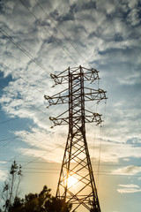 View of the power line against the clouds of blue sky in the sunlight. Electric, technology.