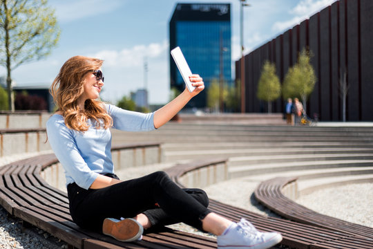 Woman making selfie photo using tablet at free wifi area in city space