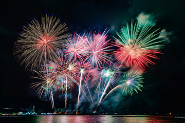 Amazing beautiful colorful fireworks display on celebration night, showing on the sea beach with multi color of reflection on water