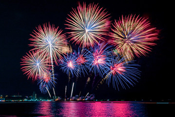 Amazing beautiful colorful fireworks display on celebration night, showing on the sea beach with multi color of reflection on water