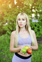 Beautiful fitness woman with apple outdoors.
