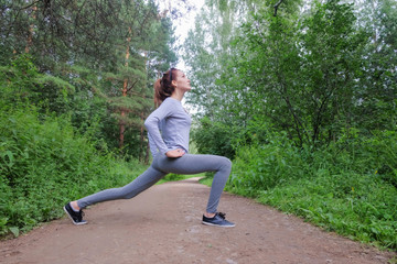 Athletic happy brunette woman working out. Girl in sportswear running in the park in summer. Woman jogging in nature.