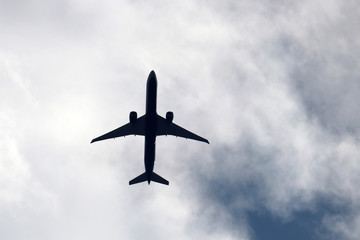 Airplane silhouette in the sky close up. Commercial plane taking off on background of white clouds