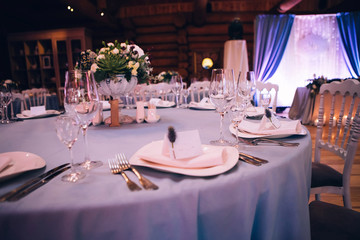 Beautiful decorated elegant wedding table for dinner with floral white bouquets, candlesticks and a white tablecloth glasses and porcelain plates