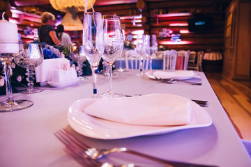 Beautiful decorated elegant wedding table for dinner with floral white bouquets, candlesticks and a white tablecloth glasses and porcelain plates