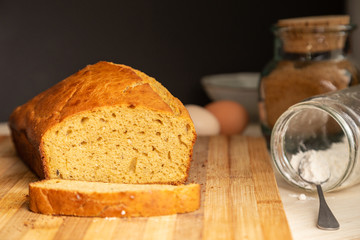Delicious sponge cake sliced on a wooden surface with ingredients in the background