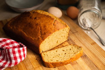 Delicious sponge cake sliced on a wooden surface with ingredients in the background