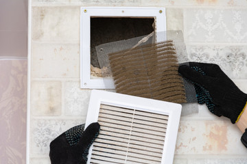 repair service man removing a dirty air filter on a house so he can replace it with a new clean....