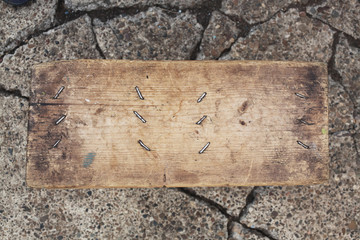 Old board with nails hammered on the pavement.