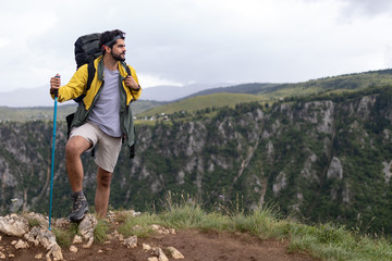 Young man traveling with backpack hiking in mountains