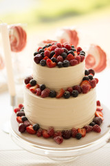 Beautiful cake covered with icing cream, summer berries on the top. Style and food photography