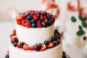 Beautiful cake covered with icing cream, summer berries on the top. Style and food photography