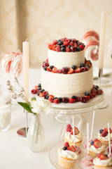 Beautiful cake covered with icing cream, summer berries on the top. Style and food photography