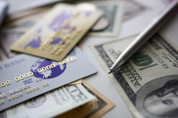 Banking plastic card and silver pen lying on big amount of US money