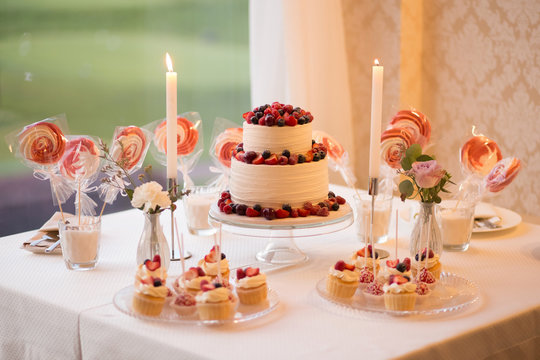 Beautiful cake covered with icing cream, summer berries on the top. Style and food photography