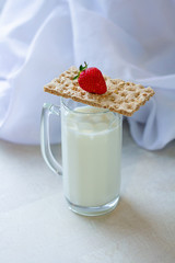 milk in a glass for beer. dry dietary bread, red strawberries on a white wooden kitchen table, morning, breakfast fitness and food cooking. white background, healthy lifestyle