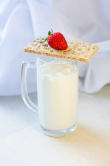 milk in a glass for beer. dry dietary bread, red strawberries on a white wooden kitchen table, morning, breakfast fitness and food cooking. white background, healthy lifestyle