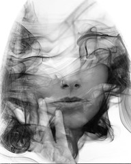 Fototapeta premium Double exposure portrait of a sensual model gently touching her face combined with a photography of smoke