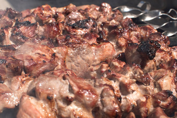 Grilled kebab cooking on metal skewer. Roasted meat cooked at barbecue. BBQ fresh meat chop slices. Traditional eastern dish, shish kebab. Grill on charcoal and flame, picnic, street food 