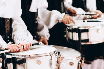 A closeup of the hands of a drummer at a parade. Children's ensemble in white shirts. White new...