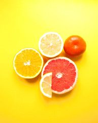 Flat lay of cut ripe juicy grapefruit, lemon and orange on yellow background. Citrus pattern.