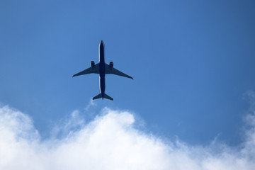 Airplane in the blue sky with white clouds. Commercial plane in a flight close up, bottom view