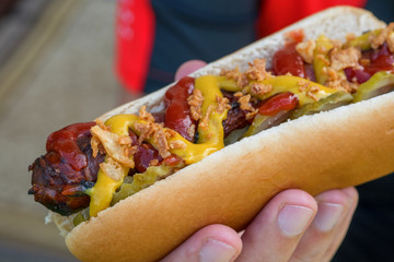 Hot Dog with grilled bacon wrapped sausage, ketchup, yellow mustard, fried onion and pickles