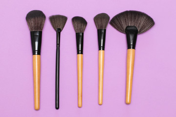 Makeup brushes on lilac background