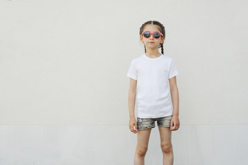 Kid girl wearing white t-shirt with space for your logo or design in casual urban style