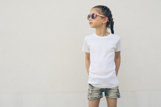 Kid girl wearing white t-shirt with space for your logo or design in casual urban style